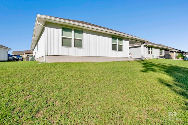 rear view of property featuring central AC and a yard