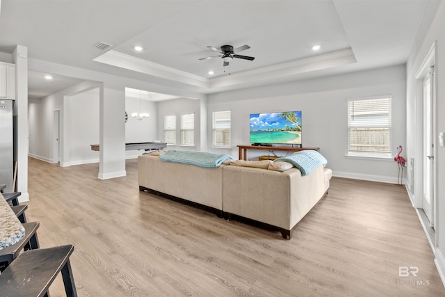 living room featuring a healthy amount of sunlight, a tray ceiling, and light hardwood / wood-style flooring