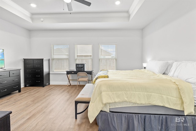 bedroom with crown molding, a tray ceiling, and light hardwood / wood-style floors