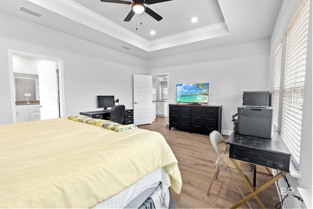 bedroom with hardwood / wood-style floors, ensuite bath, ornamental molding, and a raised ceiling