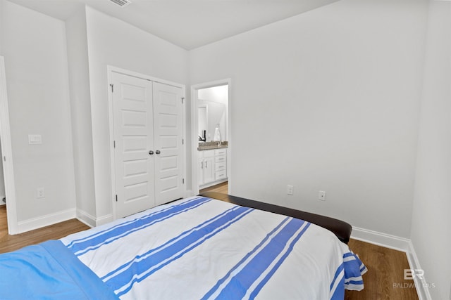 bedroom with ensuite bath, dark hardwood / wood-style flooring, and a closet