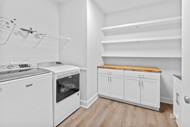 laundry area featuring separate washer and dryer, cabinets, and light wood-type flooring