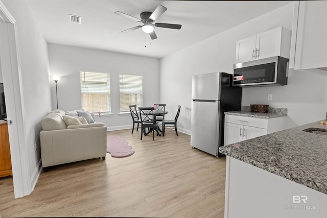 kitchen with light hardwood / wood-style flooring, ceiling fan, white cabinetry, stainless steel appliances, and stone countertops