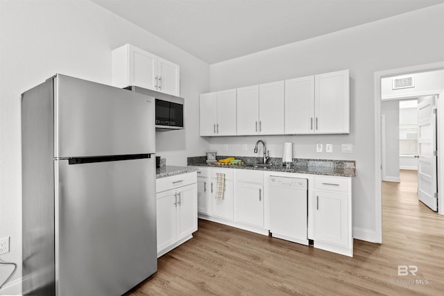 kitchen with white cabinetry, light hardwood / wood-style flooring, dark stone counters, and appliances with stainless steel finishes