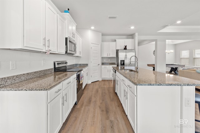 kitchen featuring sink, a center island with sink, stone counters, stainless steel appliances, and white cabinets