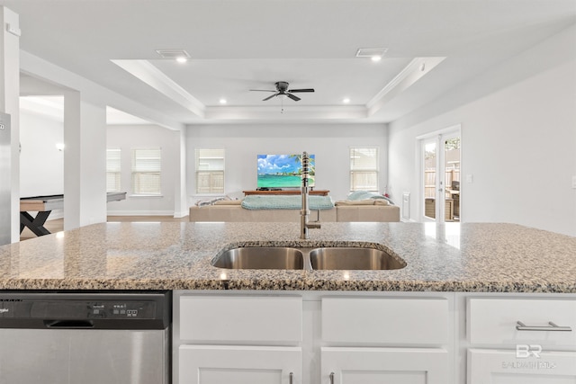 kitchen with white cabinetry, a tray ceiling, dishwasher, and light stone countertops