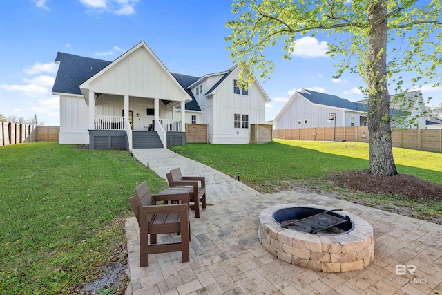 rear view of property featuring a lawn, a patio area, covered porch, and an outdoor fire pit