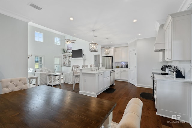 kitchen with a kitchen island with sink, hanging light fixtures, white cabinetry, stainless steel appliances, and dark hardwood / wood-style flooring