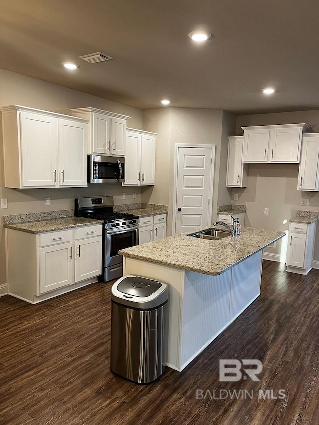 kitchen featuring stainless steel appliances, white cabinetry, a center island with sink, sink, and dark hardwood / wood-style floors