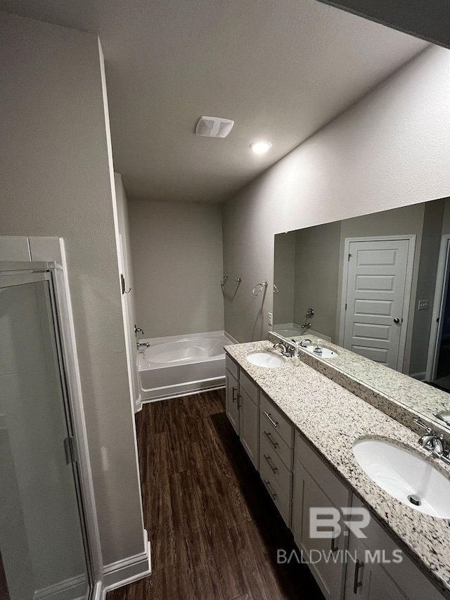 bathroom with hardwood / wood-style floors, vanity, and plus walk in shower