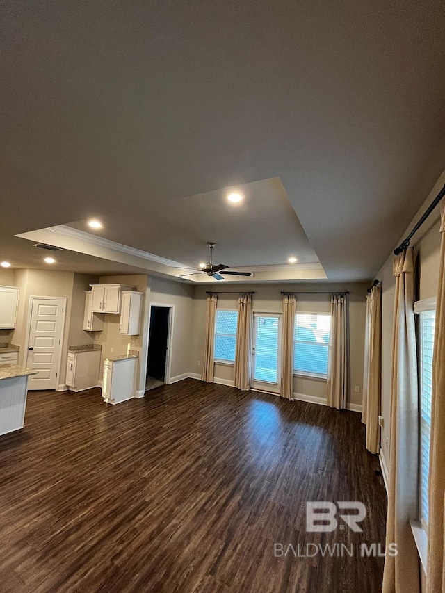 unfurnished living room with dark wood-type flooring, ceiling fan, and a raised ceiling