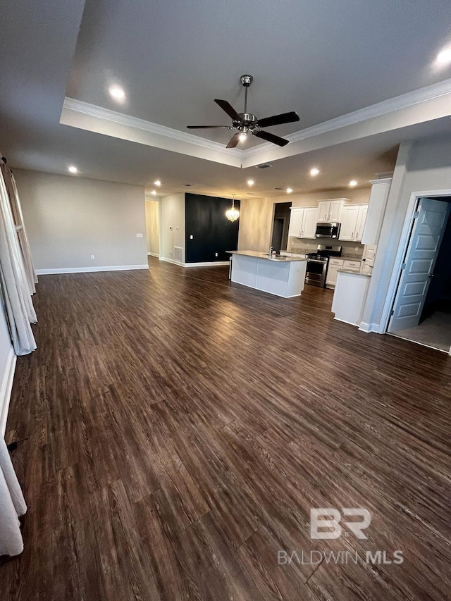 unfurnished living room with dark hardwood / wood-style flooring, ornamental molding, ceiling fan, and a raised ceiling