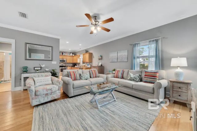 living room with crown molding, light wood-type flooring, and ceiling fan