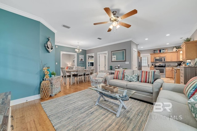 living room with ornamental molding, ceiling fan with notable chandelier, and light wood-type flooring