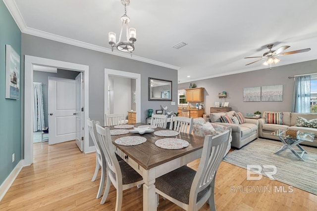 dining space with ornamental molding, ceiling fan with notable chandelier, and light wood-type flooring