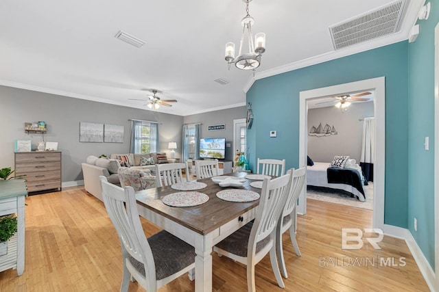 dining space featuring ornamental molding, ceiling fan with notable chandelier, and light wood-type flooring