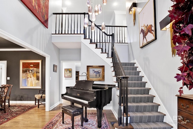 interior space with hardwood / wood-style floors, a towering ceiling, an inviting chandelier, and ornamental molding