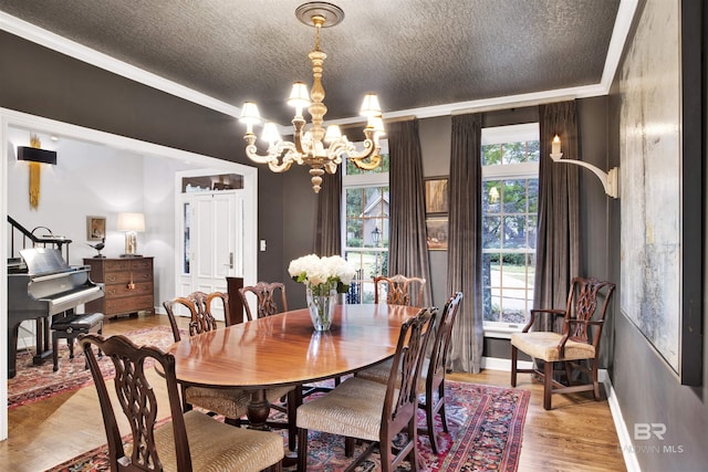 dining space with a notable chandelier, ornamental molding, a textured ceiling, and light hardwood / wood-style flooring