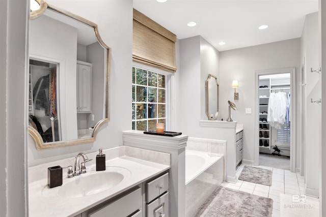 bathroom featuring tile patterned flooring, vanity, and a relaxing tiled tub