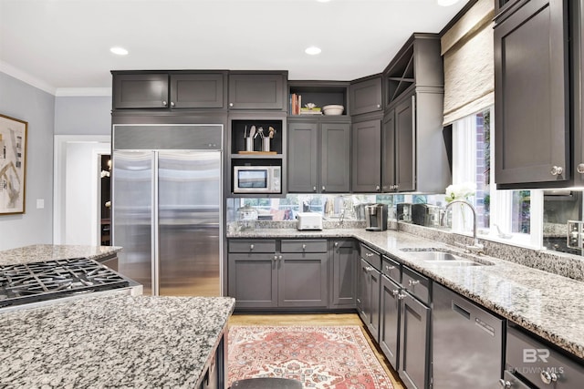 kitchen featuring light stone countertops, sink, stainless steel appliances, light hardwood / wood-style flooring, and ornamental molding