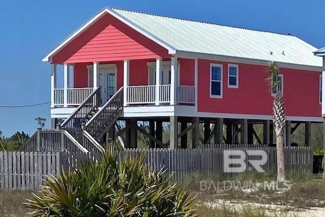 coastal home with a carport, metal roof, a porch, and stairway