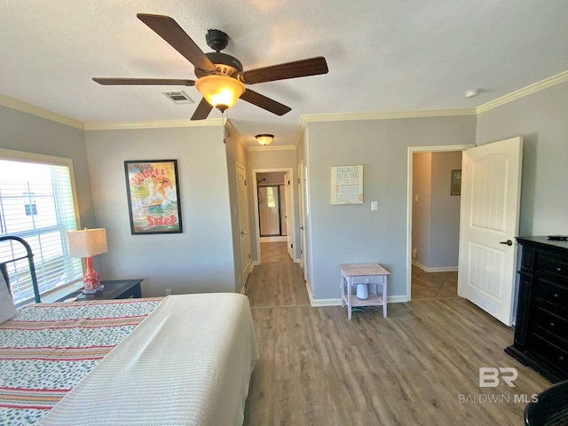 bedroom featuring crown molding, visible vents, ceiling fan, wood finished floors, and baseboards