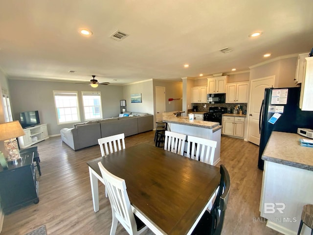 dining area with light wood finished floors, recessed lighting, visible vents, and crown molding