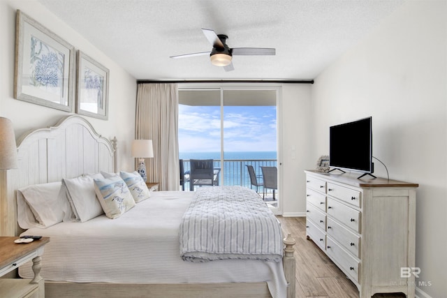 bedroom featuring a textured ceiling, light wood-style floors, access to outside, and baseboards