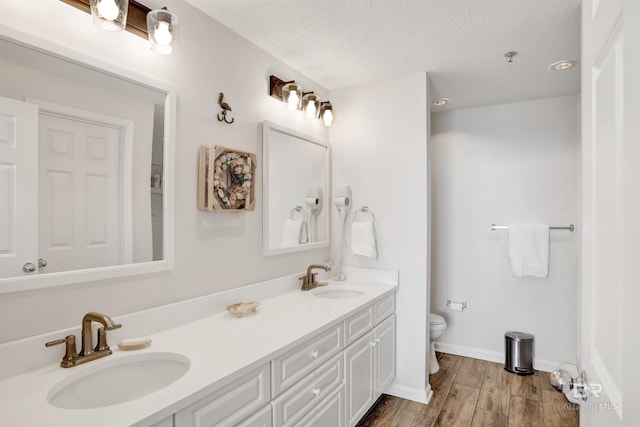 full bathroom with a sink, a textured ceiling, wood finished floors, and toilet