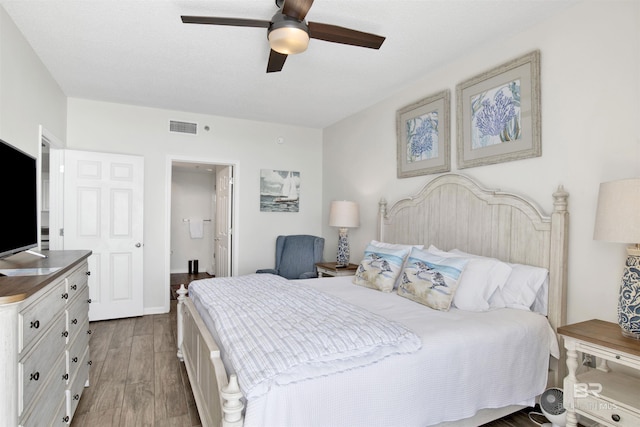 bedroom featuring a ceiling fan, visible vents, and wood finished floors