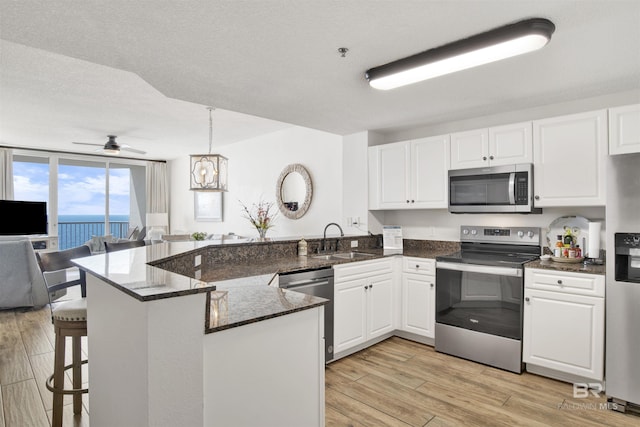 kitchen featuring white cabinetry, a sink, appliances with stainless steel finishes, and a peninsula