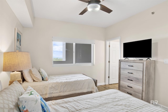 bedroom featuring a ceiling fan, baseboards, and wood finished floors