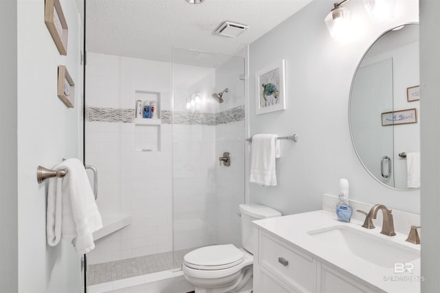 full bath featuring vanity, visible vents, a shower stall, a textured ceiling, and toilet