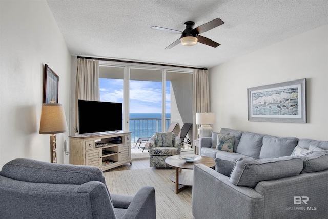 living area with light wood-style floors, ceiling fan, a textured ceiling, and floor to ceiling windows