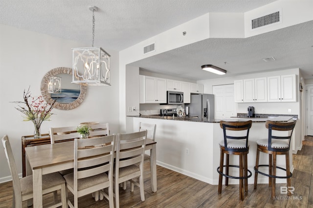 dining area with visible vents, a textured ceiling, and dark wood finished floors