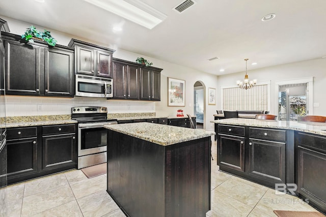 kitchen with backsplash, a chandelier, pendant lighting, a kitchen island, and appliances with stainless steel finishes