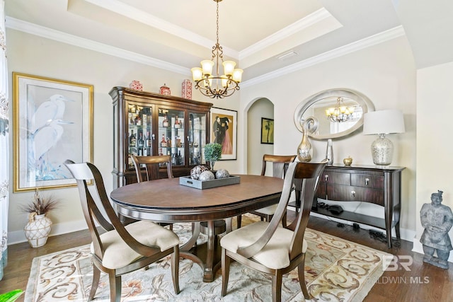 dining room featuring a chandelier, dark hardwood / wood-style flooring, a raised ceiling, and crown molding