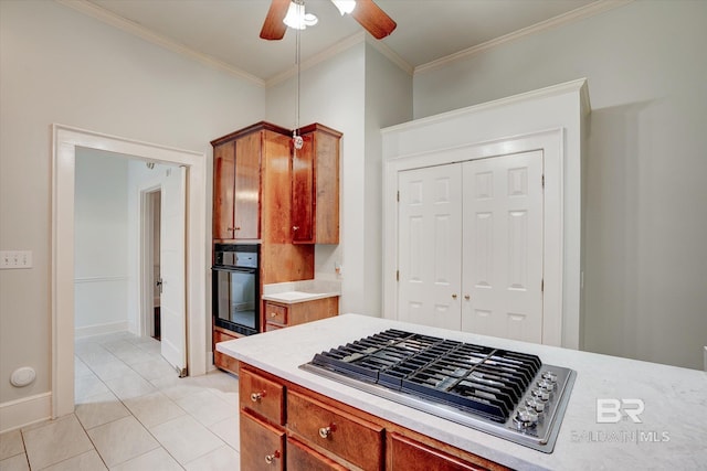 kitchen featuring a ceiling fan, stainless steel gas cooktop, ornamental molding, black oven, and light countertops