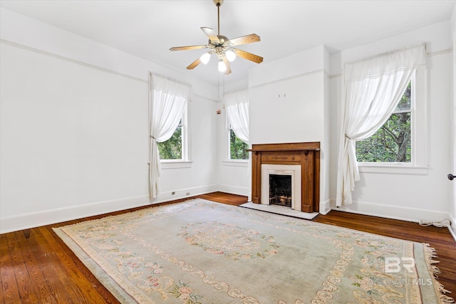 unfurnished living room with wood finished floors, baseboards, ceiling fan, and a high end fireplace