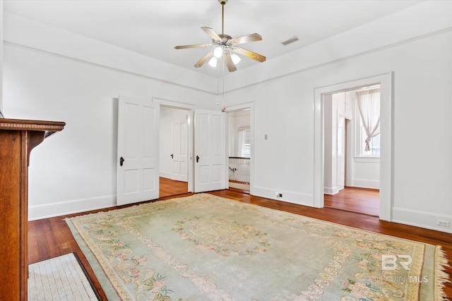 unfurnished bedroom with baseboards, a ceiling fan, visible vents, and wood finished floors