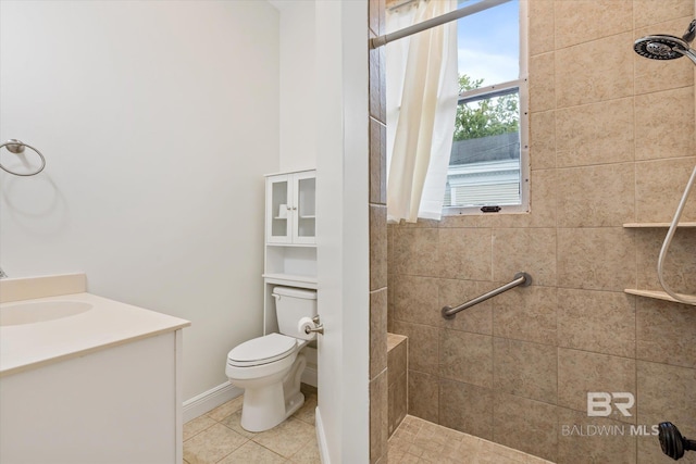 bathroom featuring toilet, tiled shower, vanity, and tile patterned flooring