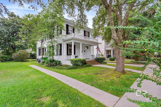 view of front of property featuring a balcony, central air condition unit, a porch, and a front lawn