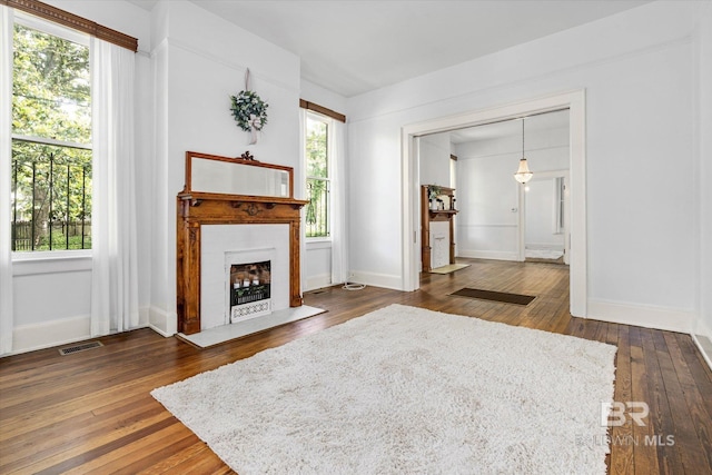 living room with baseboards, a healthy amount of sunlight, visible vents, and dark wood-type flooring