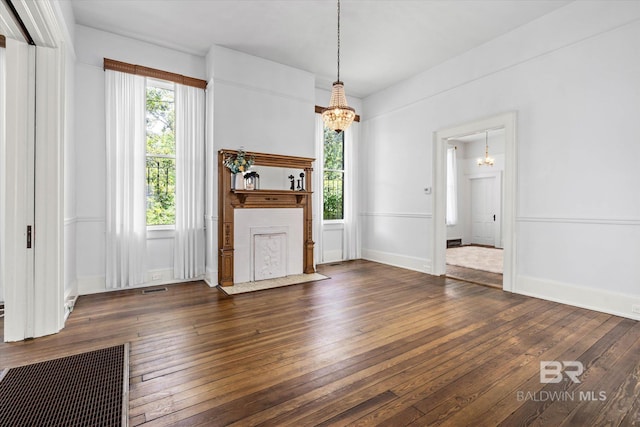 unfurnished living room featuring visible vents, baseboards, hardwood / wood-style floors, and a notable chandelier