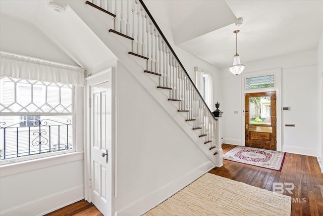 entryway with baseboards, hardwood / wood-style floors, and stairs