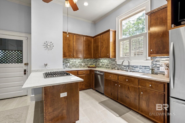 kitchen featuring stainless steel appliances, a sink, crown molding, light countertops, and tasteful backsplash