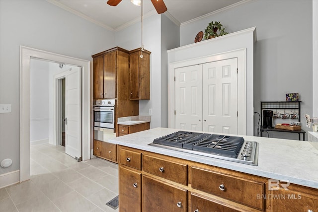 kitchen with brown cabinetry, ornamental molding, ceiling fan, light countertops, and appliances with stainless steel finishes