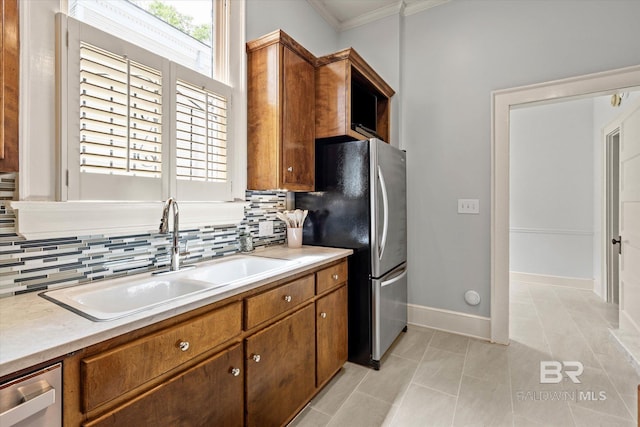kitchen with a sink, ornamental molding, stainless steel appliances, and backsplash