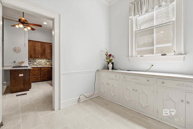 bathroom with ornamental molding, decorative backsplash, baseboards, and ceiling fan