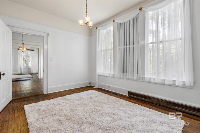 unfurnished dining area with baseboards, dark wood-style flooring, an inviting chandelier, and visible vents